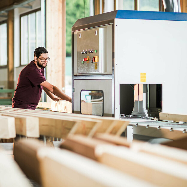 Mitarbeiter schneidet Holz an einer Maschine zu